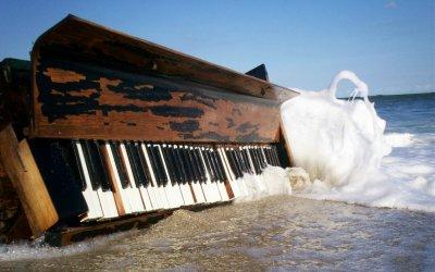 Piano on the beach being hit by waves
